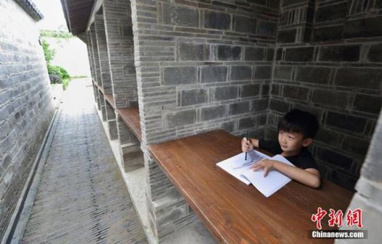 一位小朋友在中国科举博物馆内的考试号舍拍摄照片