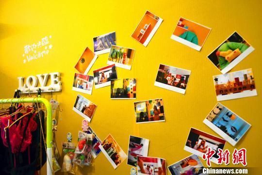 店内墙纸为橙黄色，进门处是李梦远赴上海观摩性文化展、“BigBang带你走进情趣用品店”分享会、玩转情色电影、聆听科普课堂德等活动照片墙。　唐李嫒莎　摄