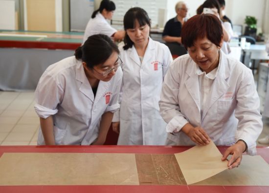 5月27日，首都博物館書畫裝裱專家樓朋竹（右一）在展示利用生物揭展劑把一幅古書畫的背紙輕鬆完整揭離。