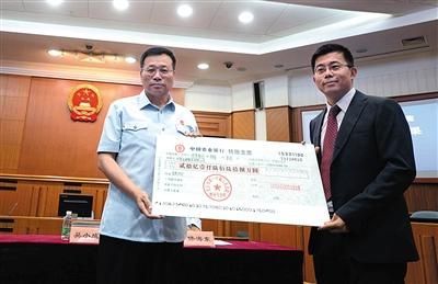 昨日，一中院执行局局长吴小成(左)将20亿元的支票，交到了华懋公司代表庄日杰的手中。新京报记者 王贵彬 摄