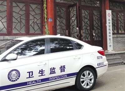 昨日，“衛生監督”執法車輛停靠在“百德堂”診所門外。診所大門左側“北京中研漢唐中醫藥研究中心”牌匾已被執法人員摘除。 本版攝影新京報記者 尹亞飛 攝