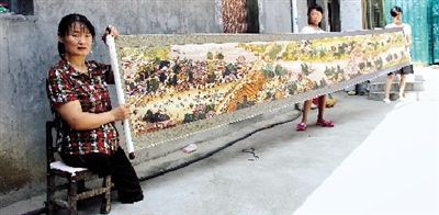 7月27日，在登封白坪乡石门村的王爱知家中，一幅装裱好的《清明上河园》十字绣被缓缓展开