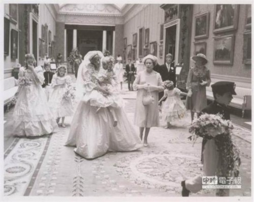 黛安娜王妃穿着美丽的婚纱，抱起小花童，笑容可掬十分亲切。(图片取自metro)
