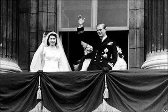 伊丽莎白女王与菲利普亲王在阳台上挥手示意。(网页截图)