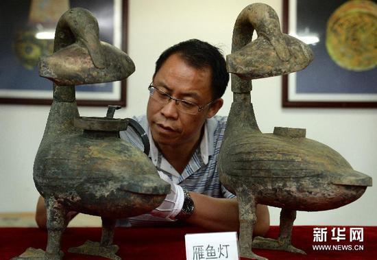 考古人员在查看海昏侯墓出土的青铜雁鱼灯(8月6日摄)。