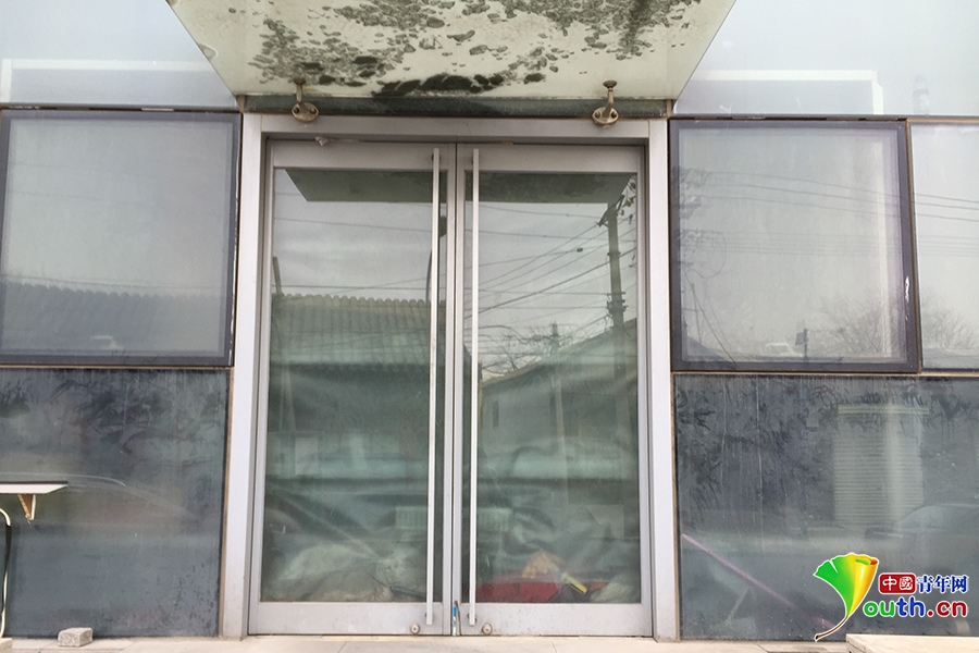 在大廈背面，從玻璃門往裏看，地上堆著雜物。 中國青年網記者 杜美辰 攝