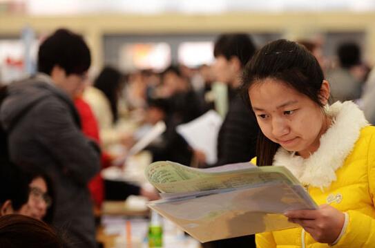 3月19日，山东省青岛市一高校招聘会现场，一名大学生在查看招聘企业资料。