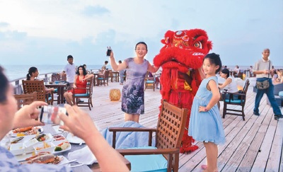 图为马尔代夫班多斯岛上，中国游客与舞狮合影留念。新华社记者 杨梅菊摄