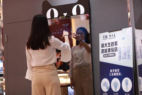 在深圳周大生智能体验店内，一位导购员正在“智能魔镜”前操作如何进行饰品的“虚拟试戴”体验。 