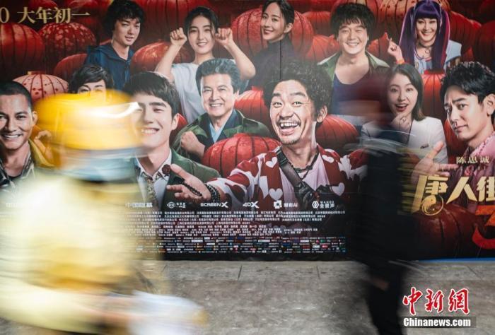 资料图：2020年3月28日，行人经过位于北京市朝阳区望京地区的一家电影院的户外广告。中新社记者 侯宇 摄
